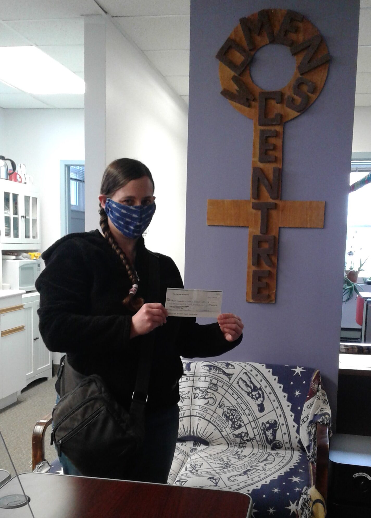 A member of Clay Collective delivering donation cheque to the Women’s Centre.